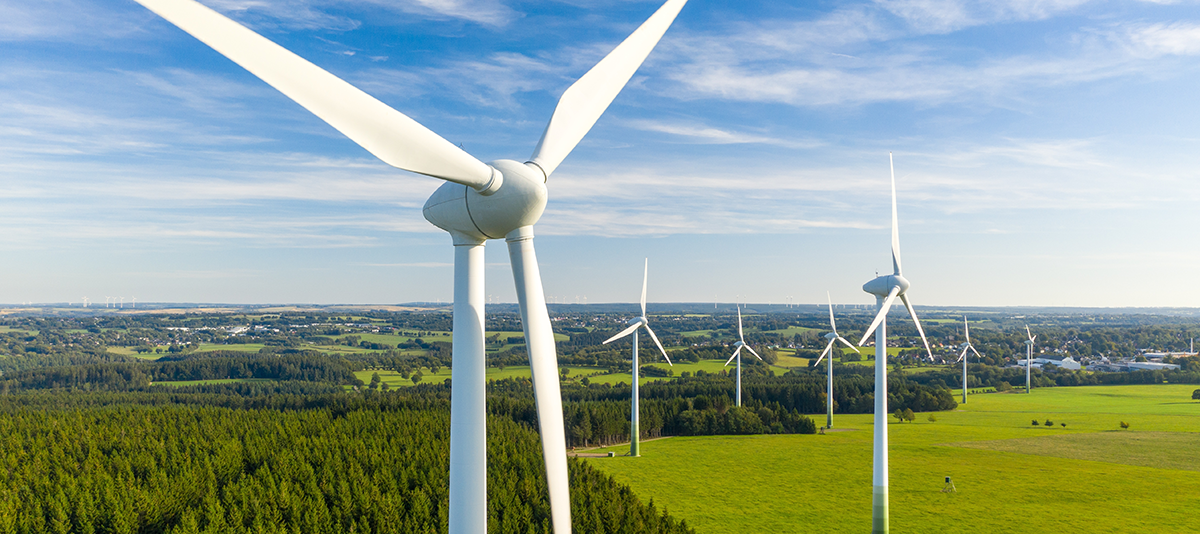 Wind turbine on an open field, in the background and distance you can see more wind turbines